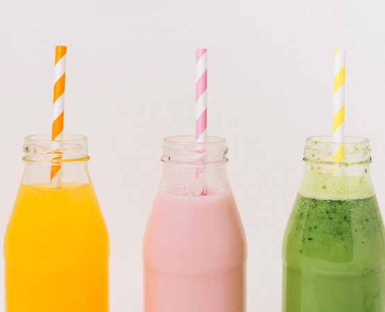 assorted delicious fruit smoothies in bottles with straws