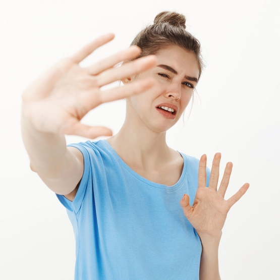 donna disgustata e infastidita che protegge il viso dalla luce alzando le mani