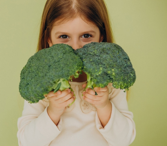little girl isolated holding green raw broccoli