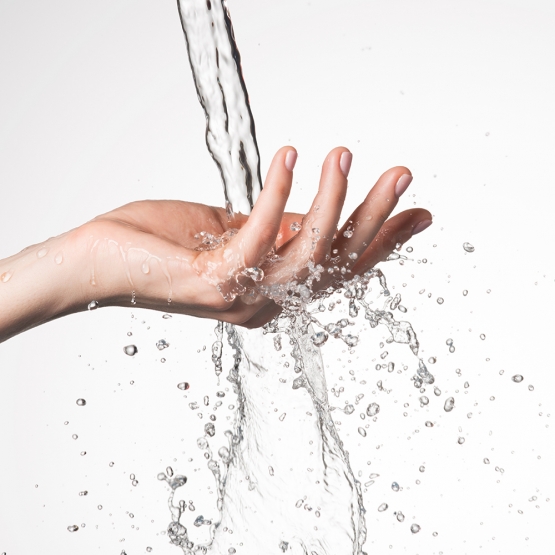 mano della donna del primo piano sotto il flusso di spruzzi d acqua concetto di cura della pelle