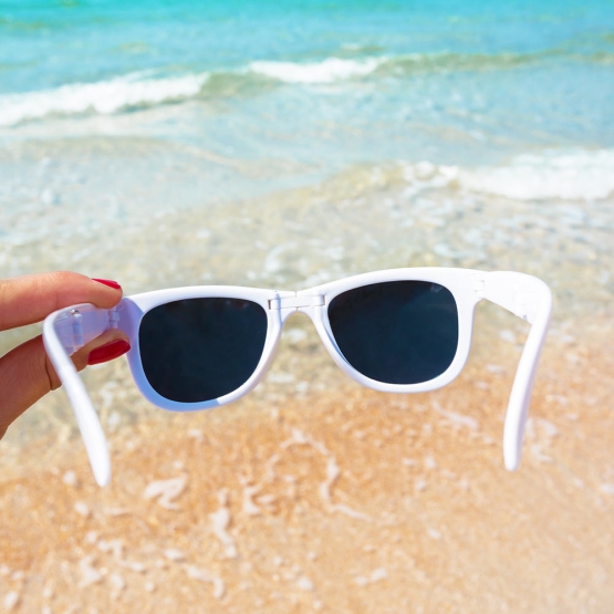 occhiali da sole in mano sullo sfondo della spiaggia