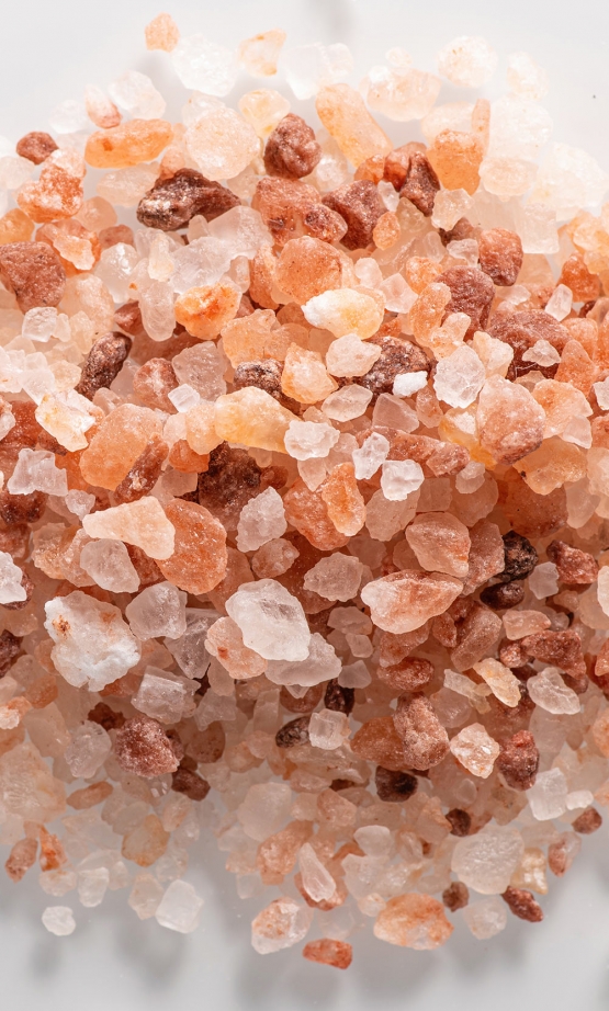 pink himalayan coarse salt on a white background close up top view