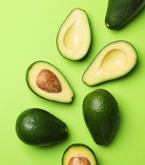 ripe fresh avocado on green background top view