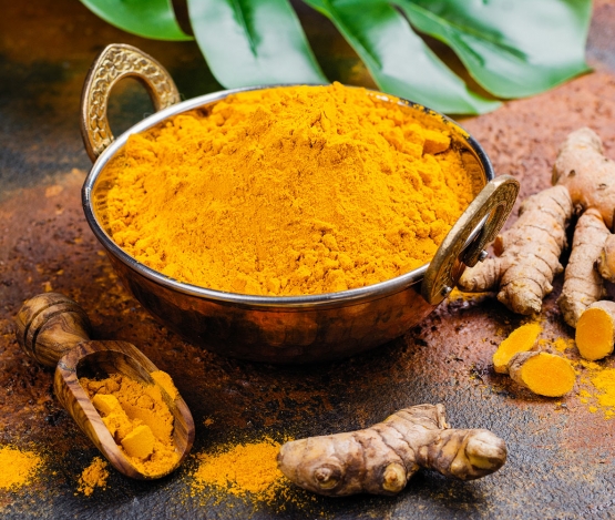 turmeric powder and fresh root on grunge background